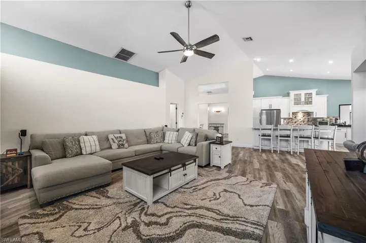 Living area with ceiling fan, high vaulted ceiling, and wood finished floors