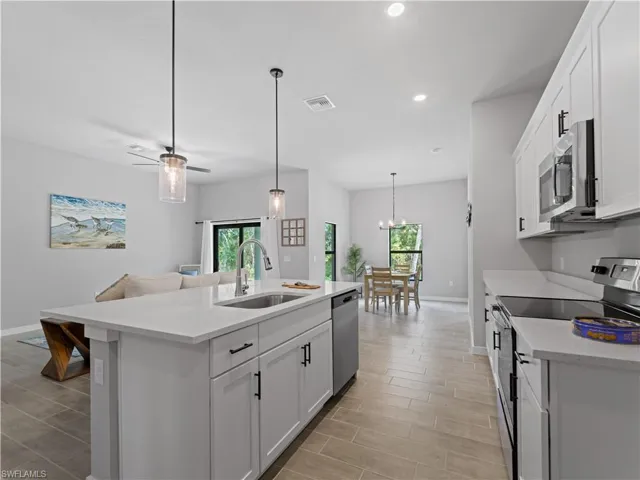 Kitchen with a healthy amount of sunlight, appliances with stainless steel finishes, sink, and an island with sink