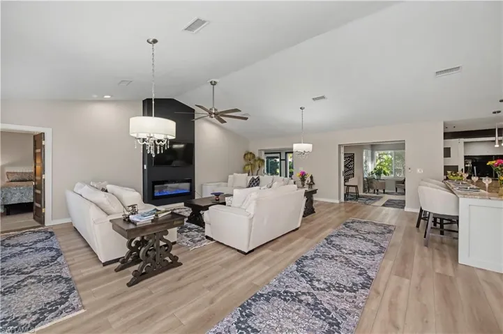 looking into great room kitchen and extended lanai under air and entrance to the primary bedroom from foyer