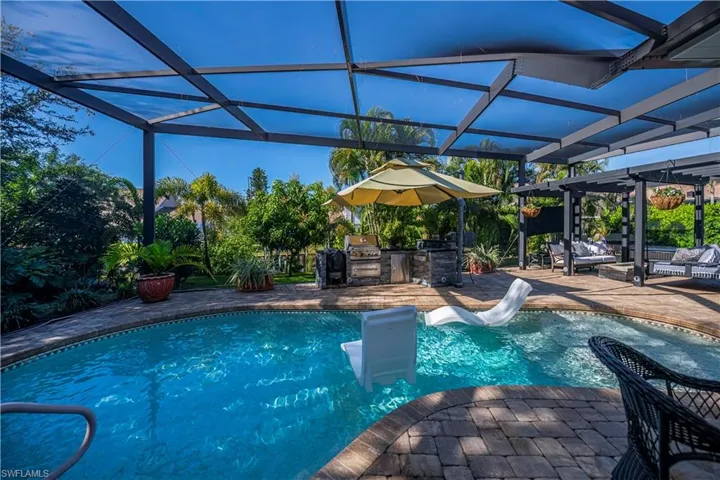 lanai with pool, outside kitchen, and pergola with swing and gas firepit