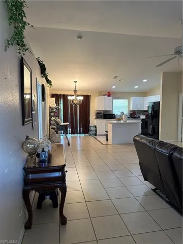 Living room featuring ceiling fan with notable chandelier and light tile patterned floors