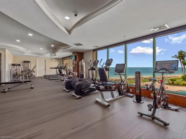 Gym featuring a wall of windows, recessed lighting, and a raised ceiling