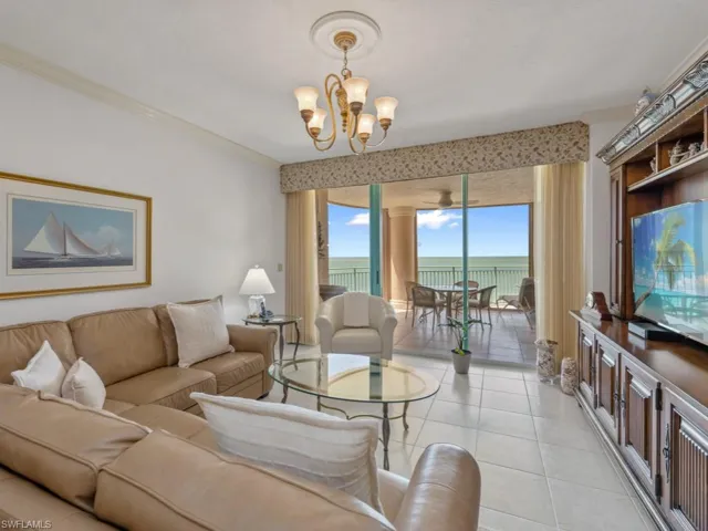 Living area with a chandelier, light tile patterned flooring, and crown molding