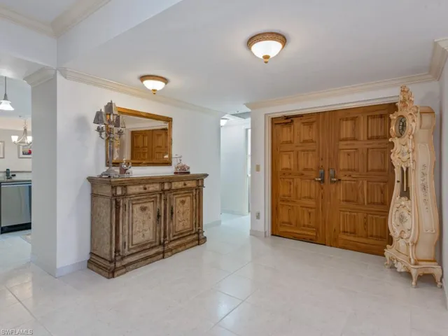 Entrance foyer with crown molding, a chandelier, and light tile patterned floors