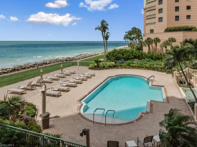 Community pool with view of water and beach and a patio