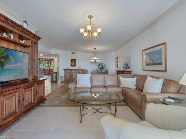 Living room featuring a chandelier, crown molding, and light tile patterned floors