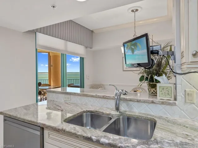 Kitchen with light stone countertops, pendant lighting, and dishwasher