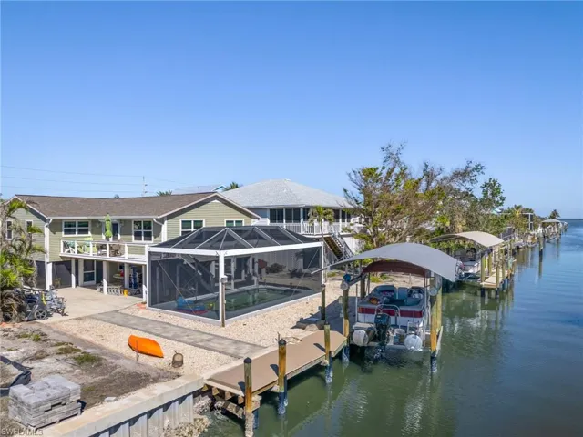 Dock featuring a lanai, boat lift, an outdoor pool, a water view, and a sunroom
