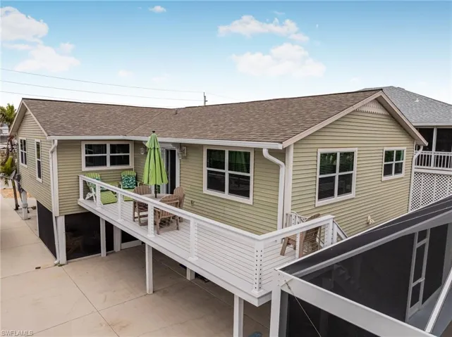 Back of property featuring a shingled roof, a balcony, and stairway