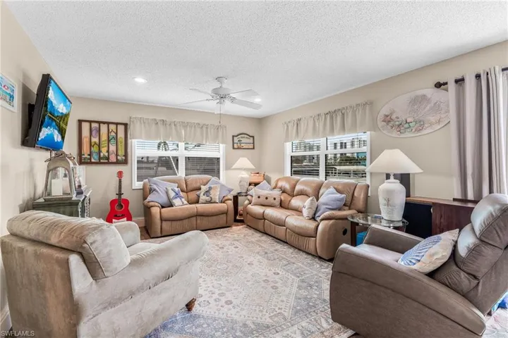 Living room with a textured ceiling, ceiling fan, and recessed lighting