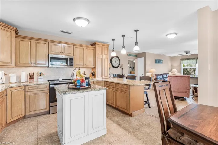 Kitchen with tasteful backsplash, appliances with stainless steel finishes, pendant lighting, a breakfast bar area, and white cabinets