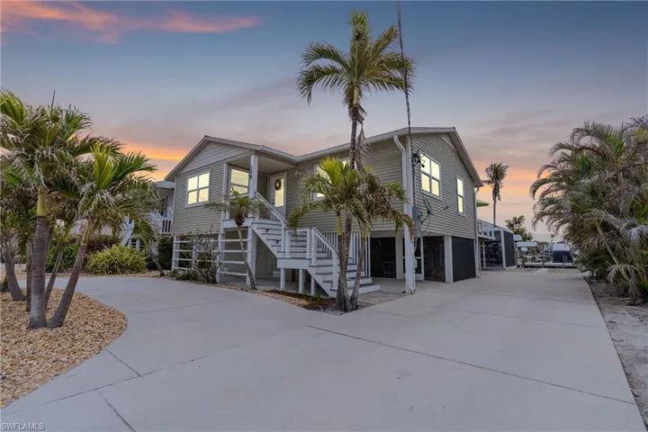 Raised beach house featuring concrete driveway and stairway