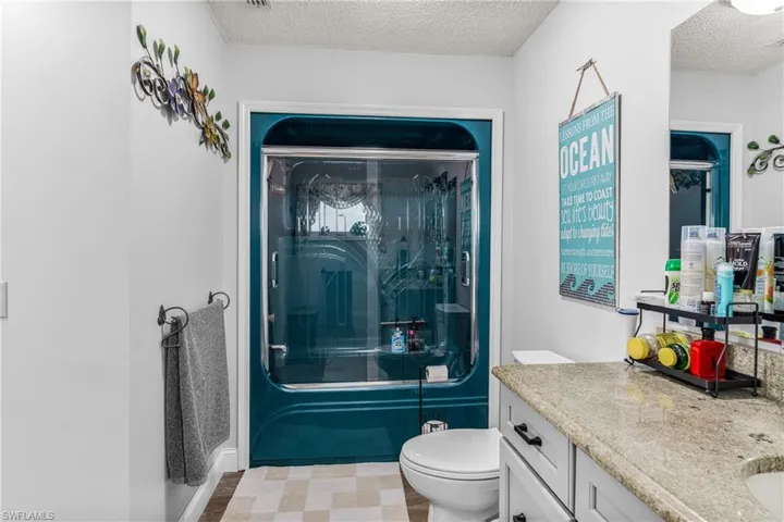 Bathroom with a shower with shower door, a textured ceiling, and vanity