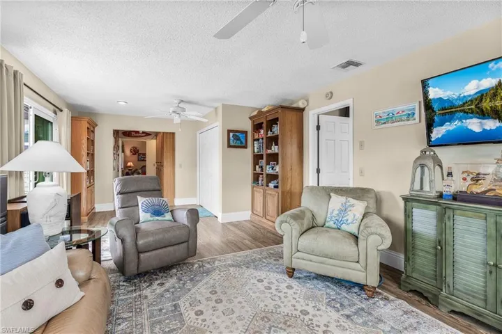 Living area with a textured ceiling, wood finished floors, and a ceiling fan