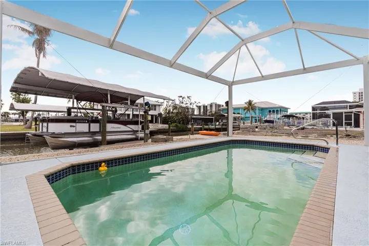 Swimming pool with boat lift, a boat dock, a water view, and a sunroom