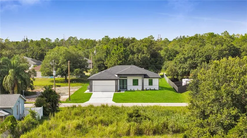 View of front of property featuring driveway, a garage, a forest view, and stucco siding