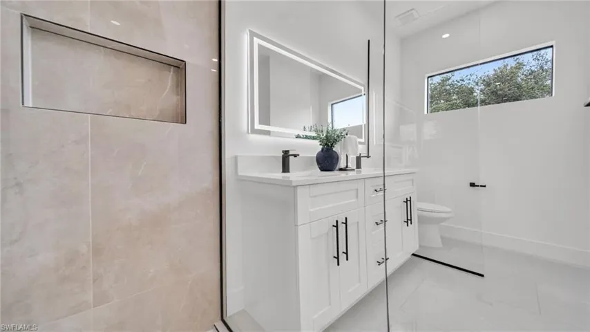 Full bath featuring double vanity and marble finish flooring