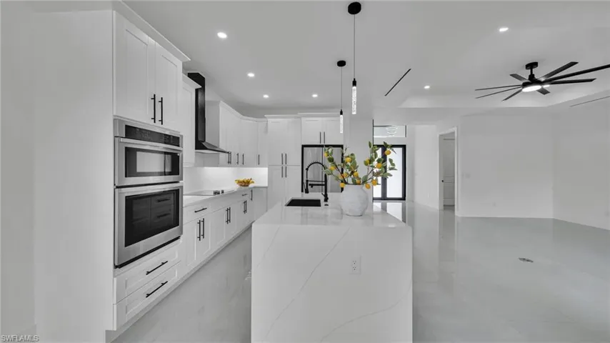 Kitchen featuring recessed lighting, appliances with stainless steel finishes, open floor plan, decorative light fixtures, and white cabinets