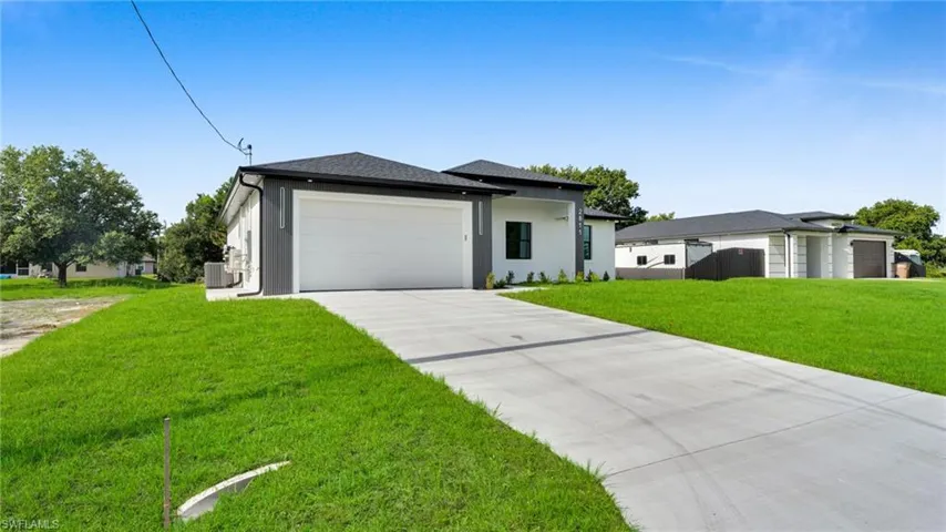 View of front of property featuring a garage, concrete driveway, a front yard, and stucco siding