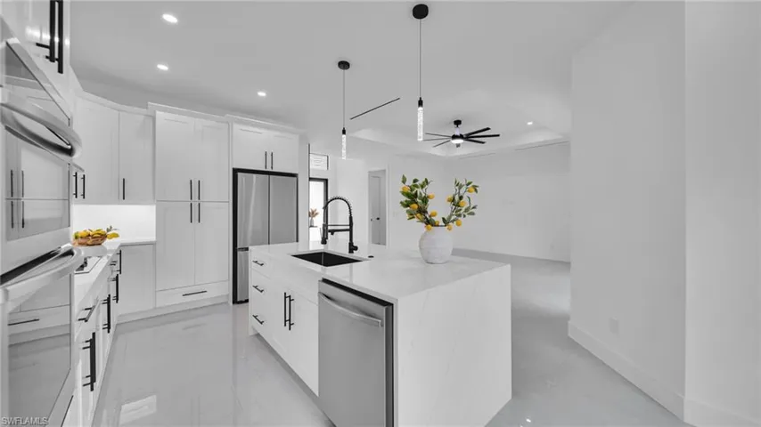 Kitchen featuring recessed lighting, appliances with stainless steel finishes, a tray ceiling, white cabinets, and pendant lighting