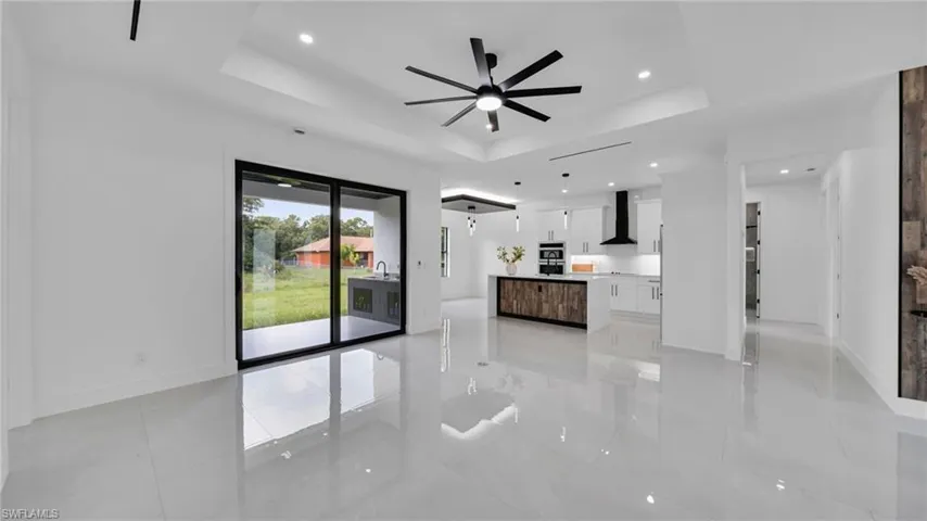 Unfurnished living room with a tray ceiling, a ceiling fan, and recessed lighting