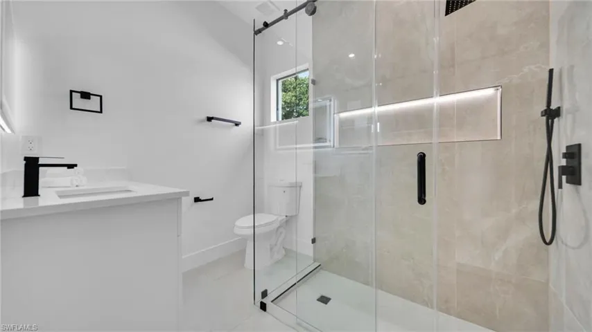Bathroom with vanity, a shower stall, and tile patterned flooring