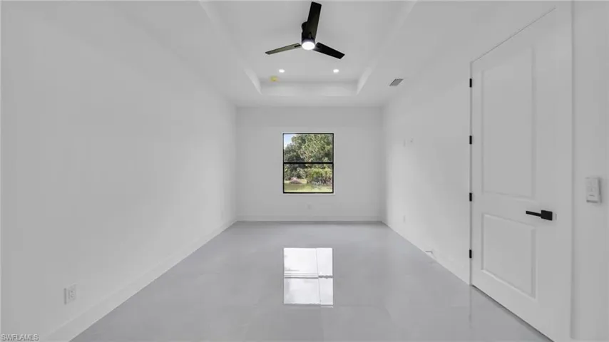 Spare room with a ceiling fan, a raised ceiling, and recessed lighting