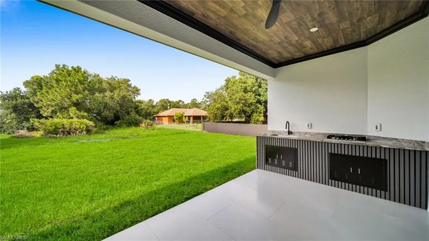 View of grassy yard featuring exterior kitchen and a patio area
