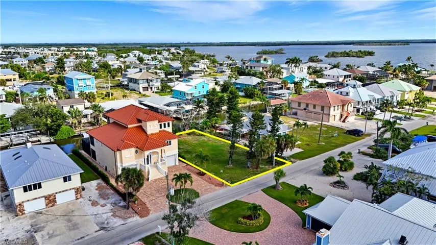 Aerial perspective of suburban area with a large body of water and property parcel outlined - Virtually Edited Image