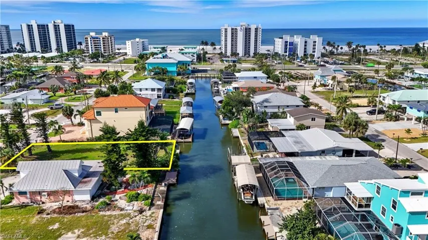 Aerial view of property and surrounding area featuring a nearby body of water and property parcel outlined - Virtually Edited Image