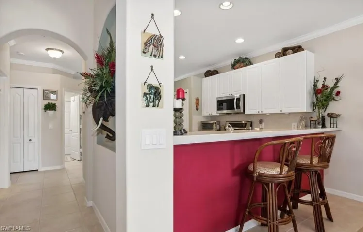 Kitchen featuring tasteful backsplash, ornamental molding, white cabinets, and appliances with stainless steel finishes