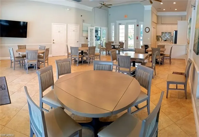 Community room in Club House with Tiled Kitchen, dining space featuring french doors, ceiling fan, and a high ceiling. Doors open to a patio area and pool area.