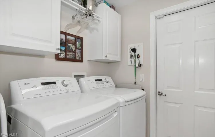 Laundry room featuring cabinets and separate washer and dryer. Tub sink in garage.