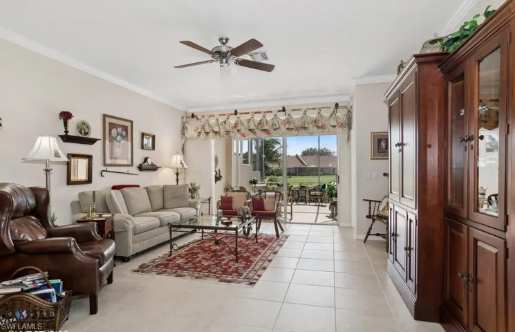 Tiled living room with ceiling fan and ornamental molding