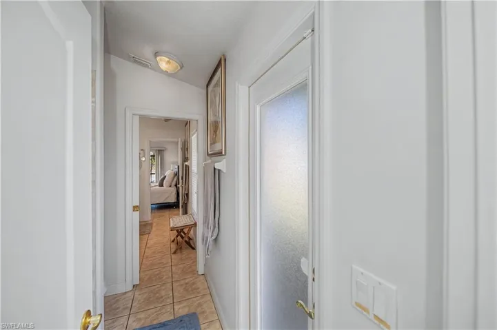 Hallway featuring vaulted ceiling and light tile patterned floors