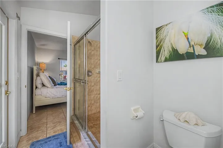 Ensuite bathroom with a shower stall and light tile patterned floors