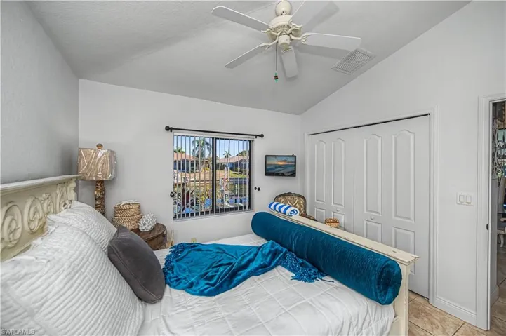 Tiled bedroom featuring lofted ceiling, a closet, and ceiling fan