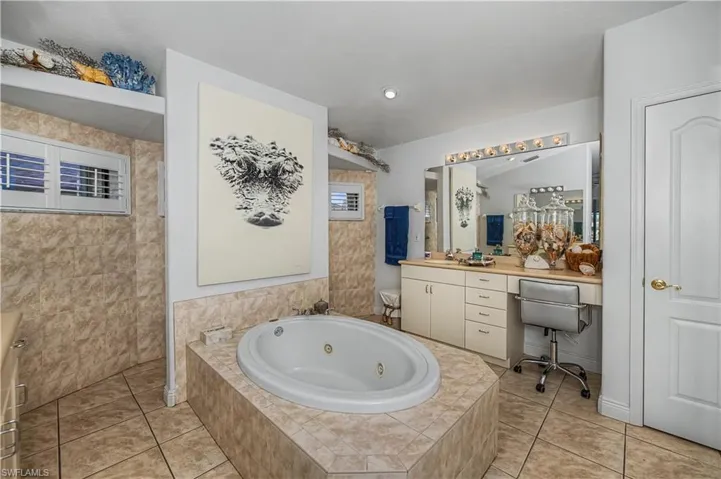 Full bathroom with vanity, a whirlpool tub, and light tile patterned flooring