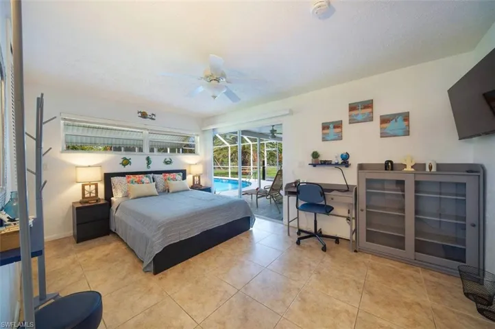 Bedroom with a sunroom, access to exterior, light tile patterned flooring, and a ceiling fan