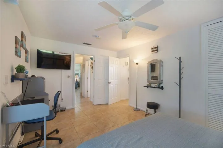 Bedroom with an office area, ceiling fan, and light tile patterned floors