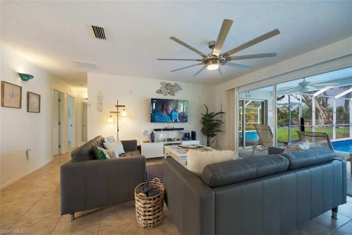 Tiled living room featuring ceiling fan, a textured ceiling, and a sunroom