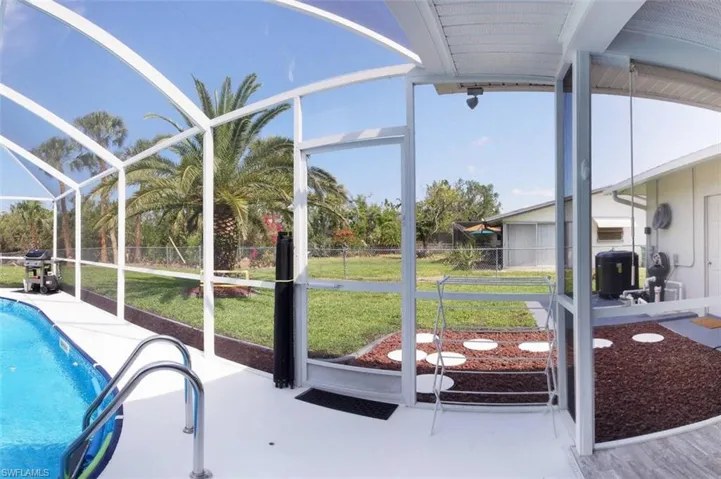 Outdoor pool featuring a sunroom, glass enclosure, a fenced backyard, and a grill