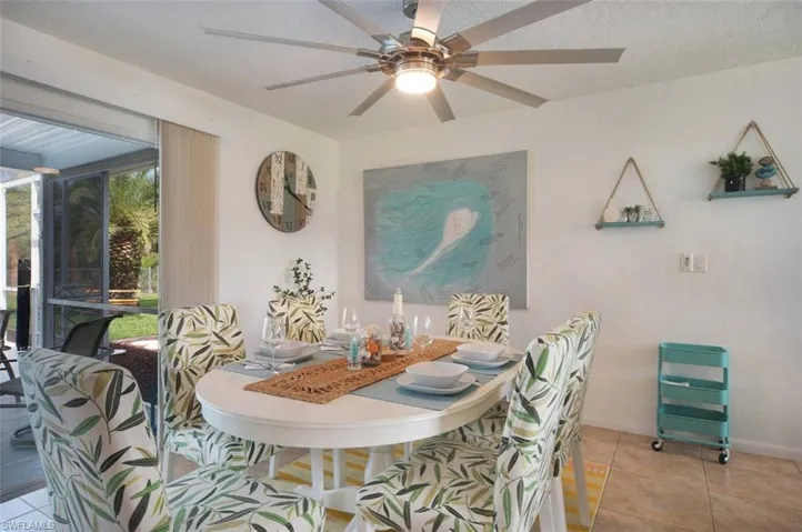 Dining space with light tile patterned flooring, ceiling fan, and a textured ceiling