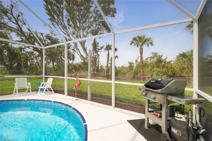 Swimming pool featuring a sunroom, a yard, a lanai, and a grill