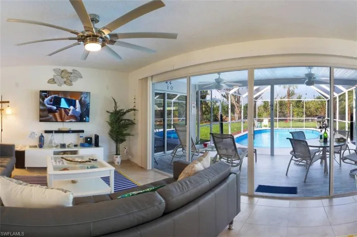 Living area with a sunroom, tile patterned floors, and a ceiling fan