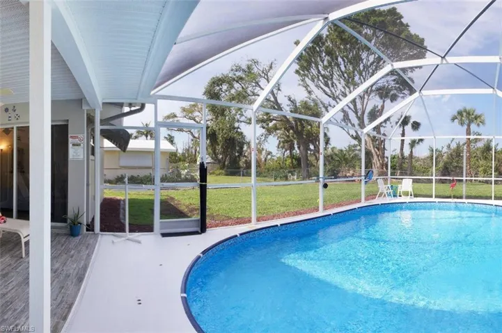 Swimming pool with a sunroom, glass enclosure, a yard, and a patio