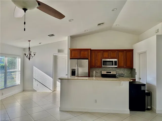 Open concept kitchen featuring wood cabinetry, stainless steel appliances, and a light-toned countertop