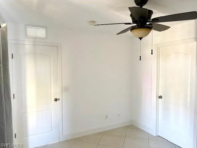 The secondary bedroom offers a comfortable, medium-sized layout with sleek tile flooring and abundant natural light. It includes a well-sized closet and convenient access to the second bathroom, creating a semi-private and versatile space ideal for guests or a growing family.