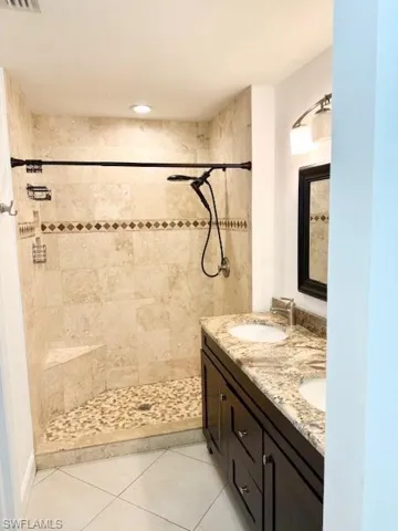 The primary bathroom features a spacious layout with a large walk-in shower and a double vanity sink, offering both comfort and functionality.