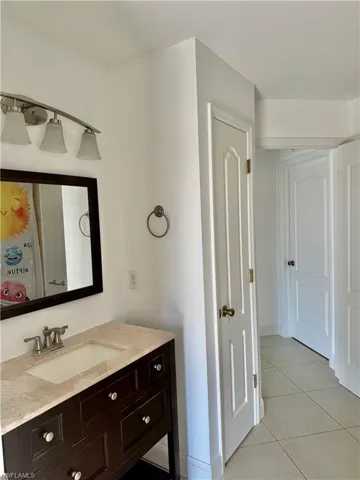 Bathroom vanity featuring a light-toned countertop, an undermount sink, and a dark wood-finish cabinet with multiple drawers and brushed nickel hardware